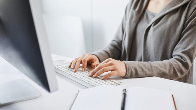 Working hard to party hard on weekends. Cropped shot of woman typing on keyboard, sitting in front of computer monitor. Freelancer translating new project, writing some notes in note pad. Office and work concept